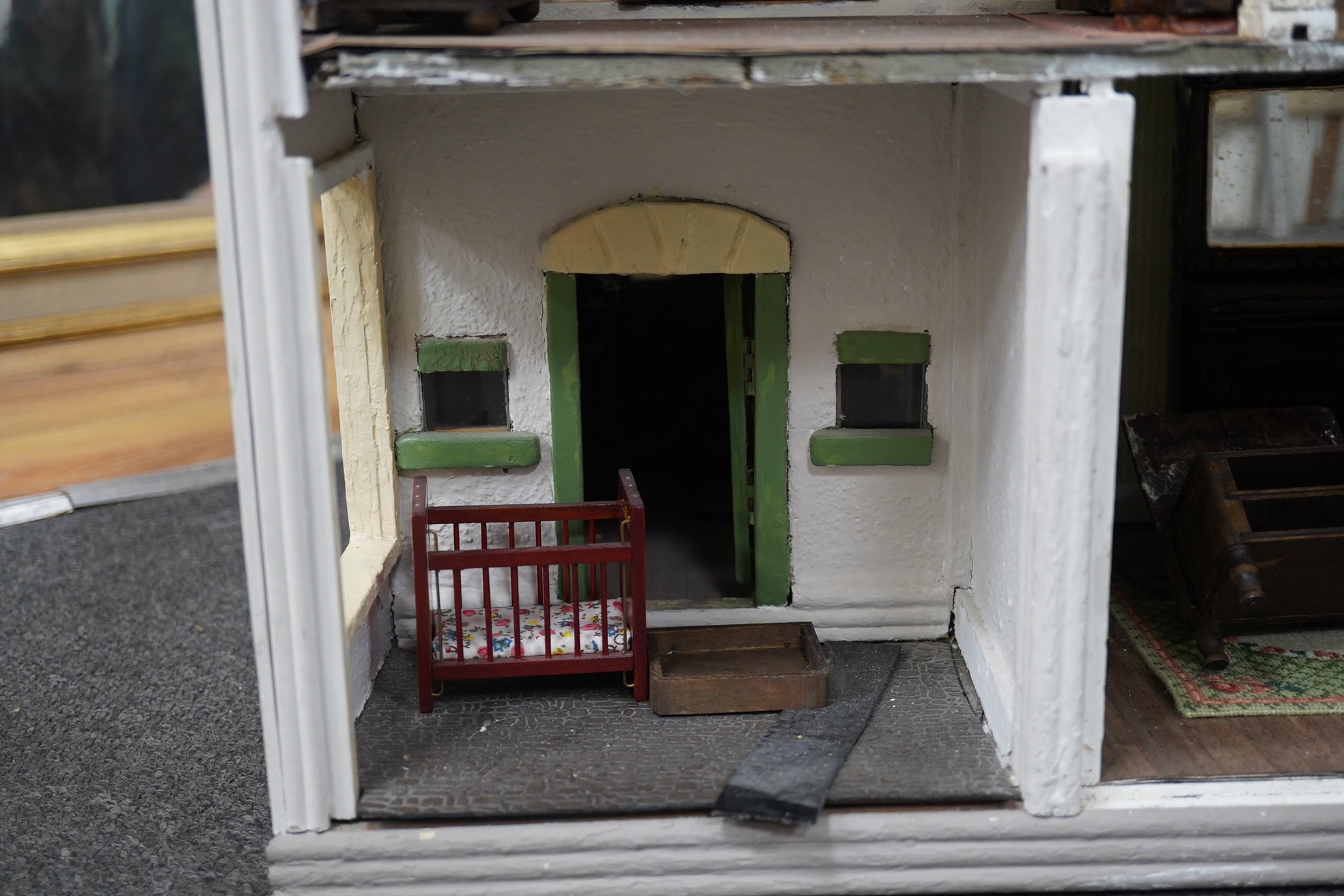 A mid-20th century green and white plywood doll's house, with a pyramid hip tiled roof, together with some plywood furniture including furniture from the Pit-A-Pat Series, height 67cm, width 54cm, depth 54cm. Condition -